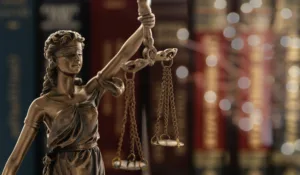 Sttaute holding scales of justice with background of books and shining light and gold leaf detail in the background.